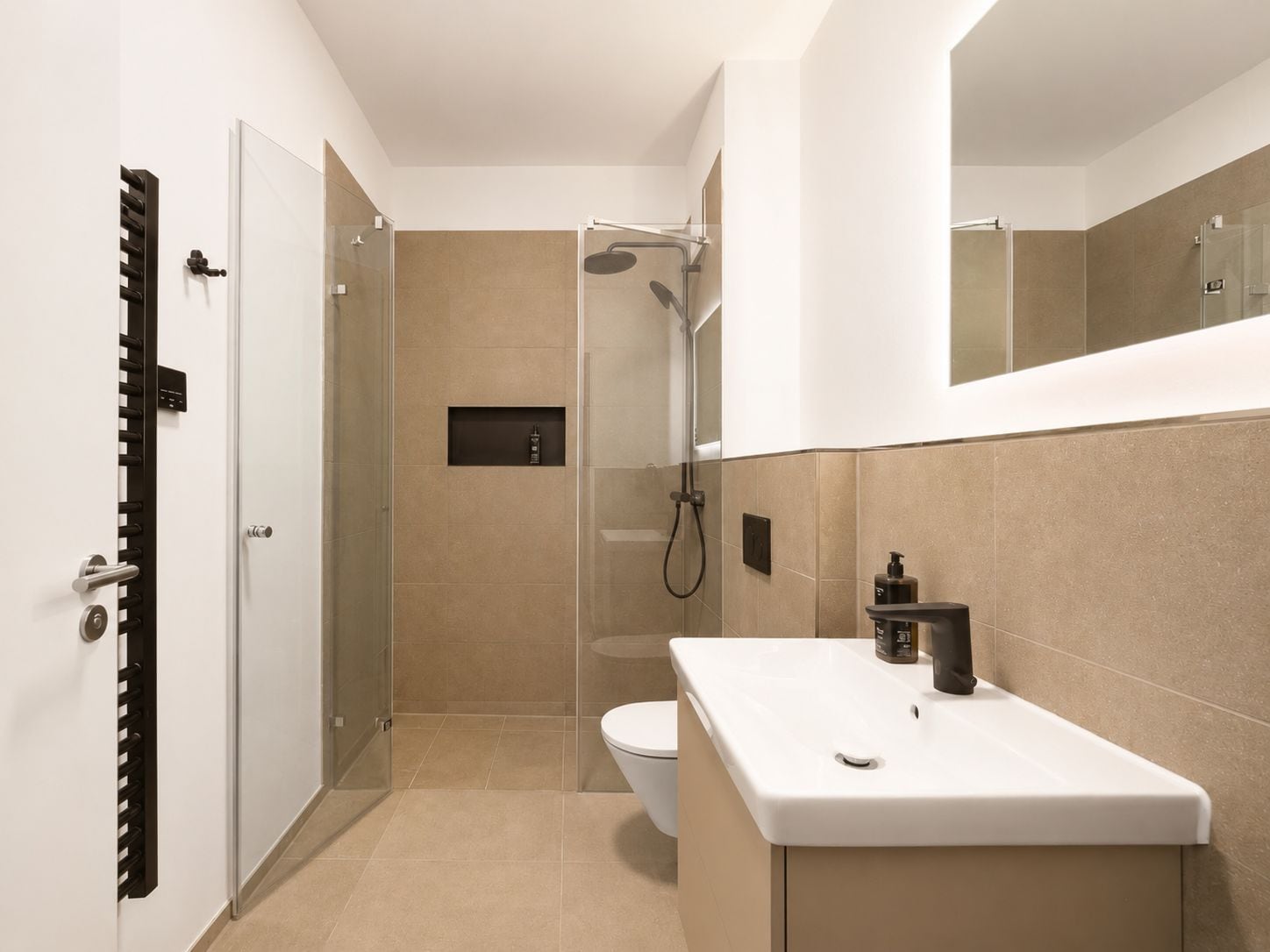 Ein modernes Badezimmer mit Dusche, Toilette und Waschbecken mit Spiegel darüber.