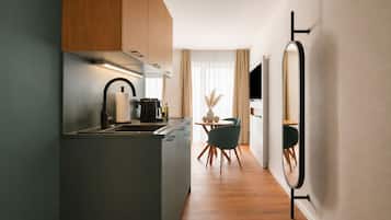 A modern kitchen with a central island, a dining area with a round table and chairs, and a large mirror on the wall.