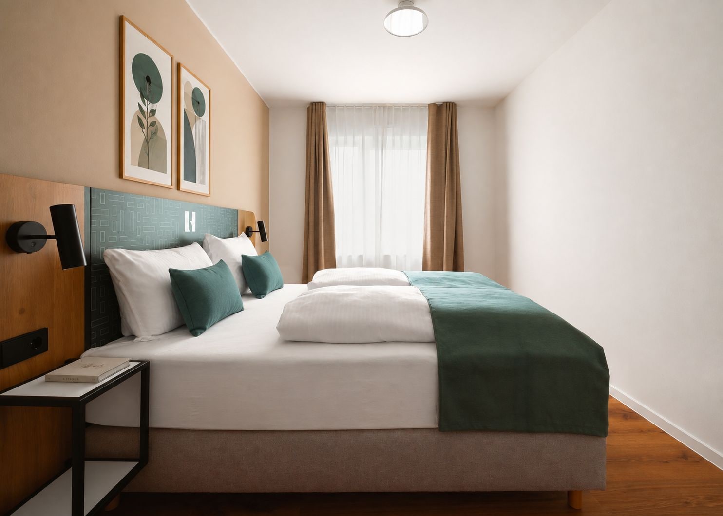 A modern hotel room with a large bed, a bedside table with a book, and a headboard with wall art.