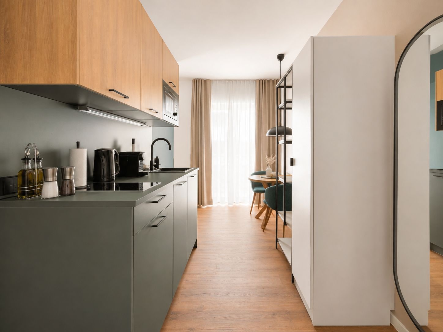 Eine moderne Küche mit grauen Schränken, einer schwarzen Arbeitsplatte und einem Essbereich mit Tisch und Stühlen.