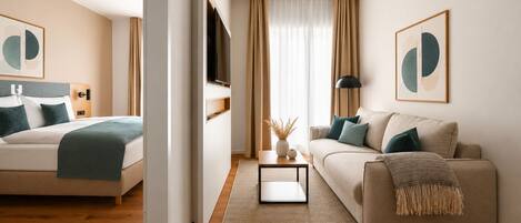 A modern hotel room with a bed, a sofa, a TV, and artwork on the walls.