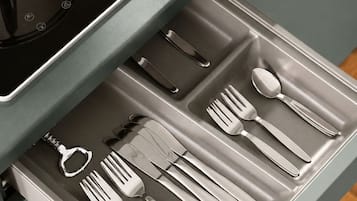 Un cajón con cubiertos ordenados, incluyendo tenedores, cuchillos y cucharas.