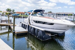 A white motorboat docked at a marina with a wooden dock and a clear sky. - Mejia's Little House - Cozy Waterfront Escape (New Port Richey)