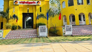 A yellow building with a sign reading 'Vishalgarh' and a QR code on the steps. - Vishalgarh Farms  (Gurugram)