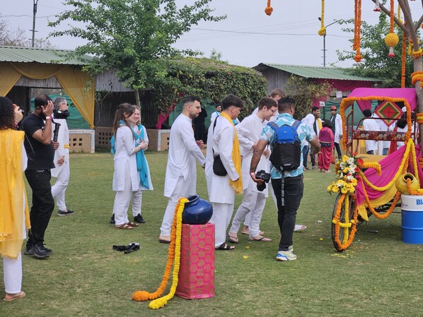 A group of people in traditional attire gathered around a decorated cart in an outdoor setting. - Vishalgarh Farms (Gurugram)