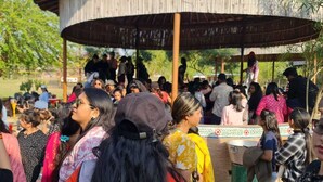 A group of people gathered under a wooden structure with a thatched roof. - Vishalgarh Farms  (Gurugram)