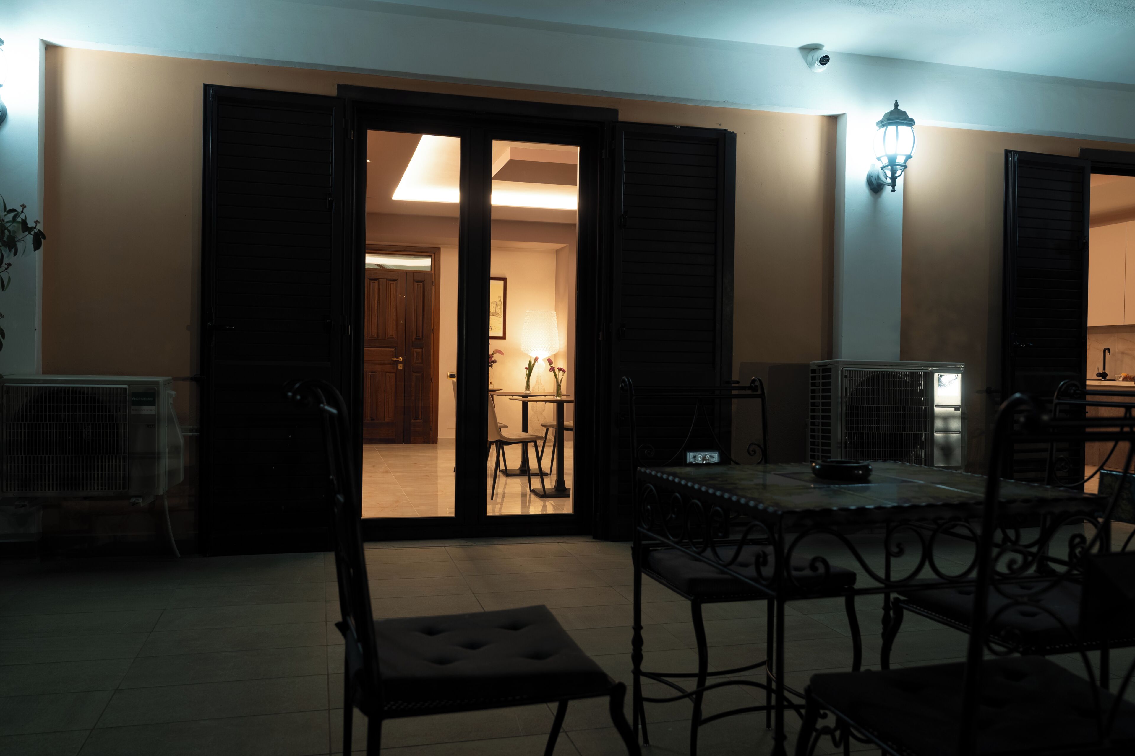 An open doorway leading to a dining area with a table and chairs, a ceiling fan, and a wall-mounted light fixture.