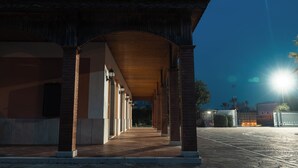 Un paseo techado con techo de baldosas, pilares de ladrillo y cielo despejado.