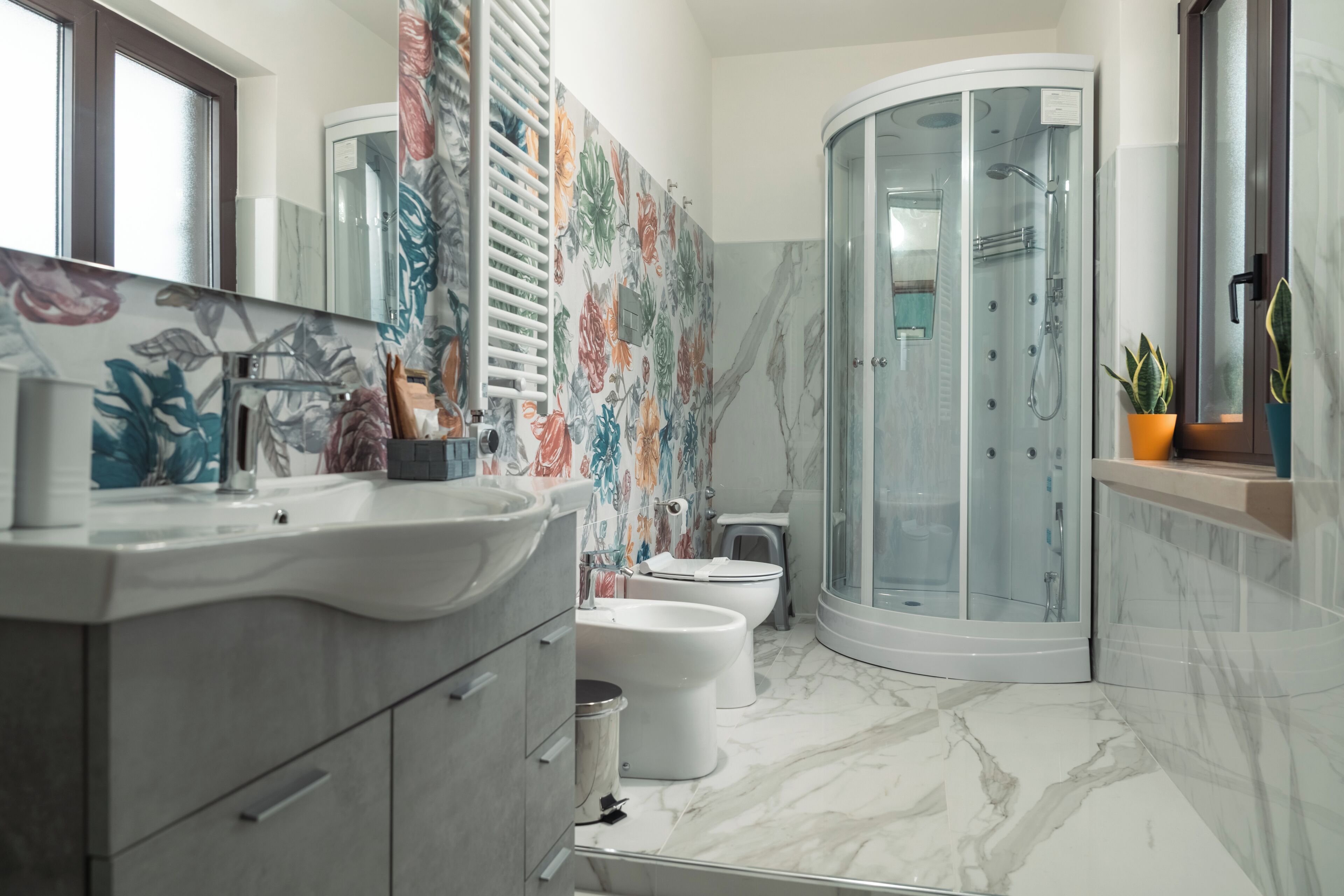 A modern bathroom with a curved shower enclosure, a toilet, and a sink with a marble countertop.