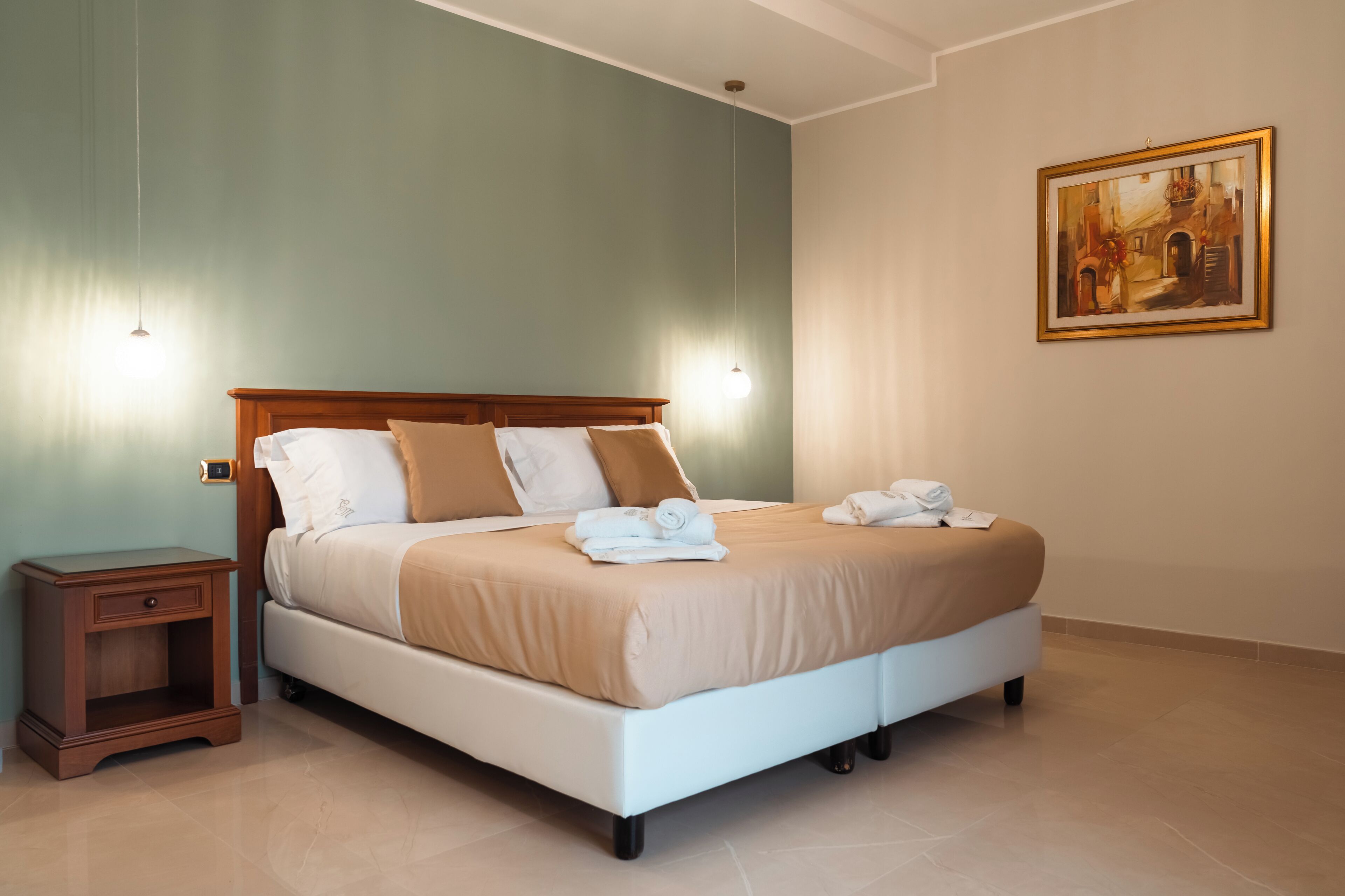 Un letto rifatto con cura, una testiera in legno, un comodino con un cassetto e un quadro appeso al muro.