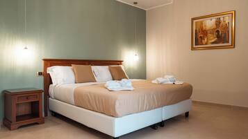 Un letto rifatto con cura, una testiera in legno, un comodino con un cassetto e un quadro appeso al muro.