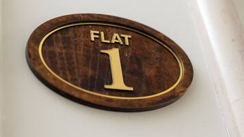 Una placa de madera con el texto 'FLAT 1' sobre una pared blanca.