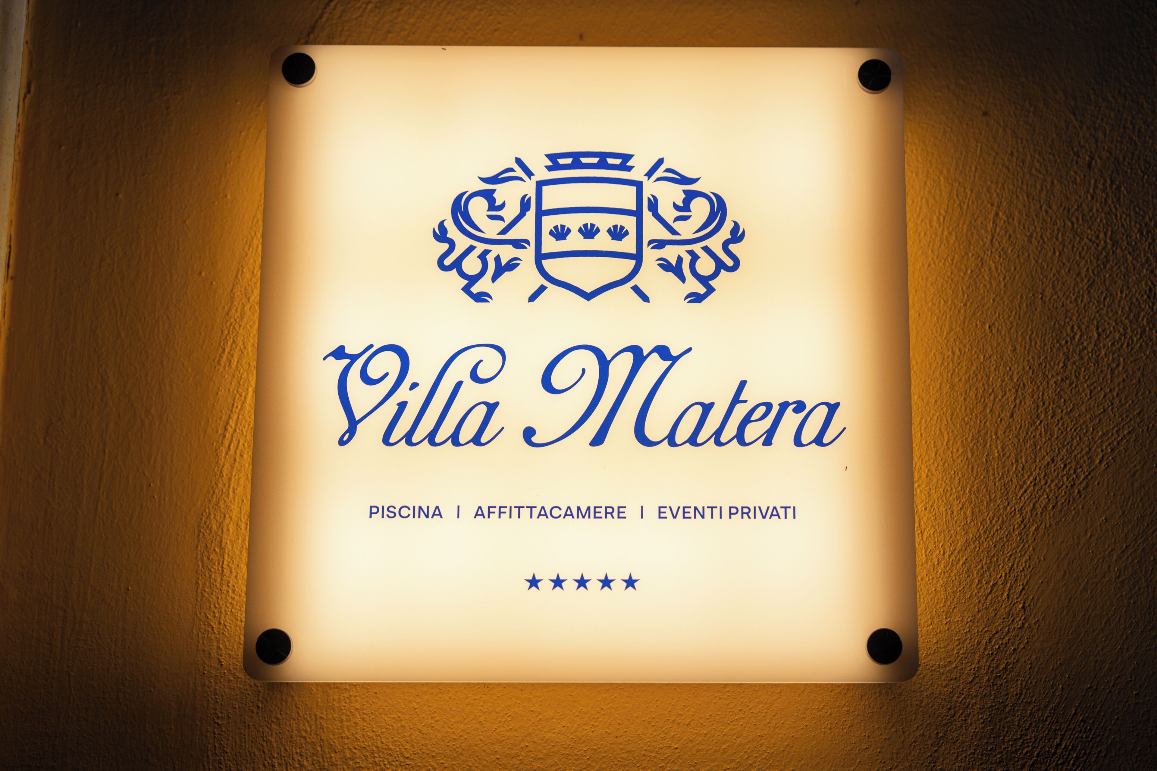 A sign with 'Villa Matera' and services like 'Piscina,' 'Affittacamere,' and 'Eventi Privati.'