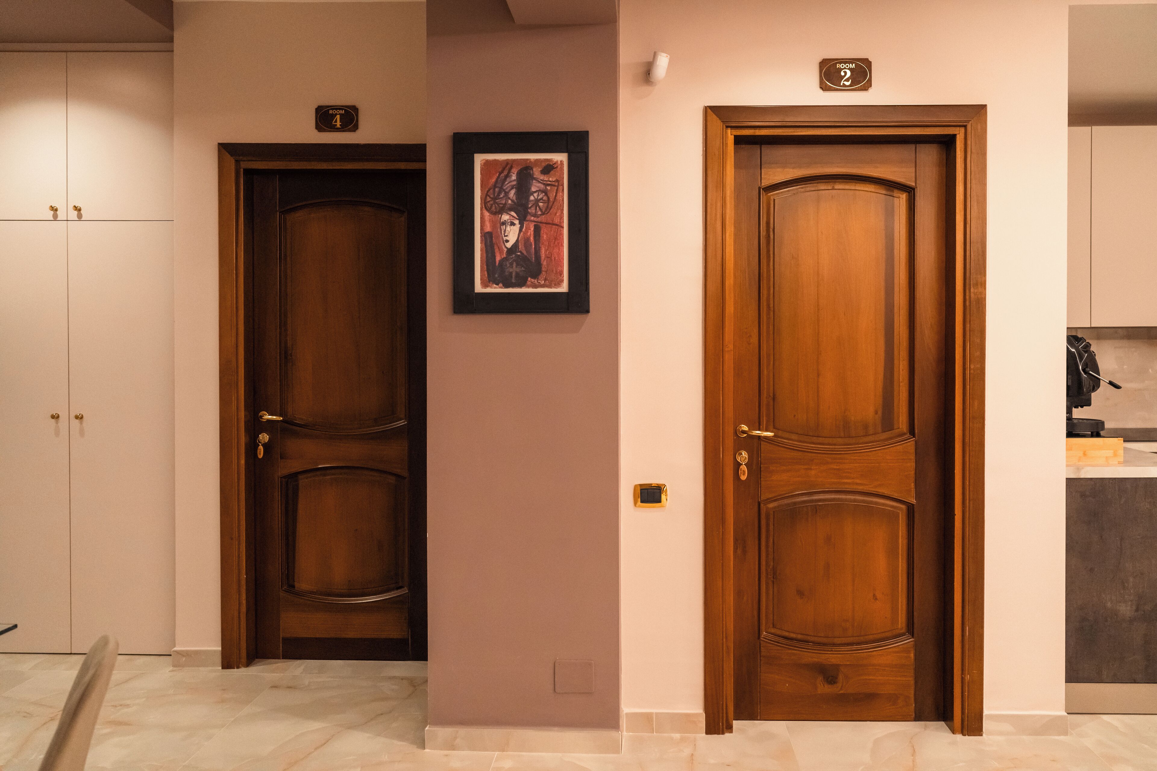 Two wooden doors with room numbers, a framed artwork, and a kitchen area.