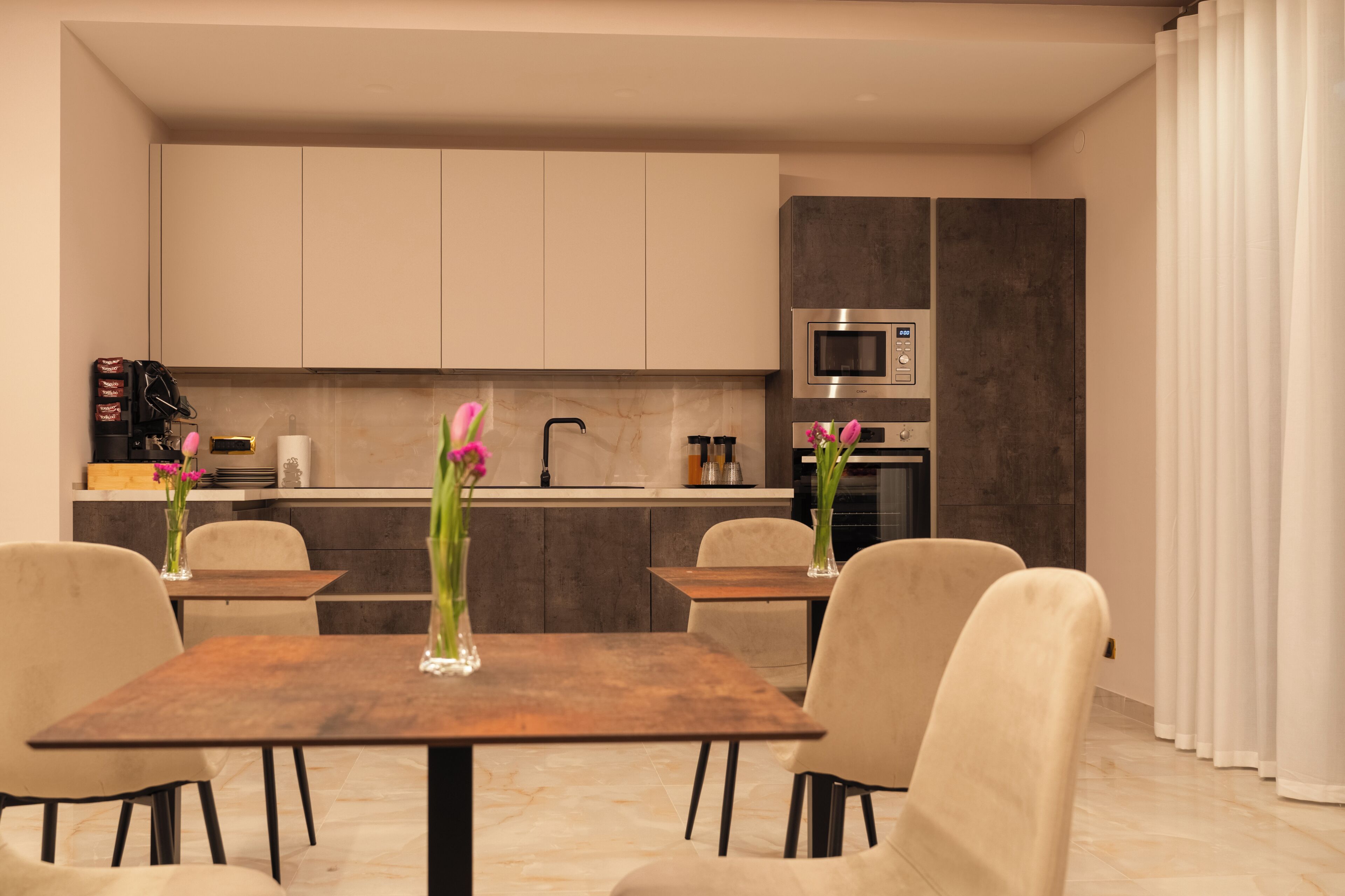 A modern kitchen with a dining area, featuring a marble countertop, a built-in oven, and a microwave.