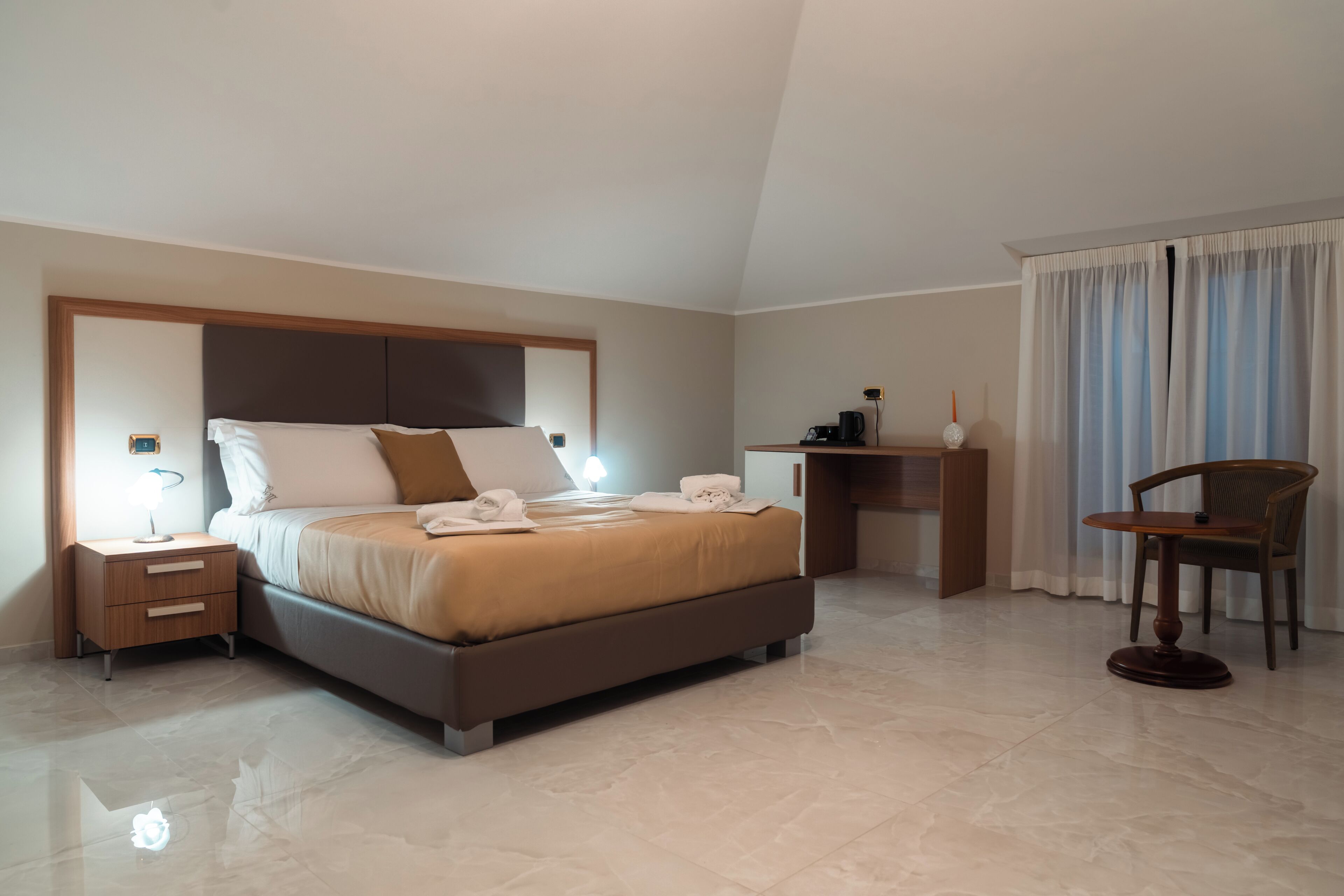 Ein Schlafzimmer mit Bett, Nachttisch, Lampe und einem Sessel.
