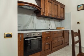 Cozinha com armários de madeira, forno embutido e backsplash de mármore.