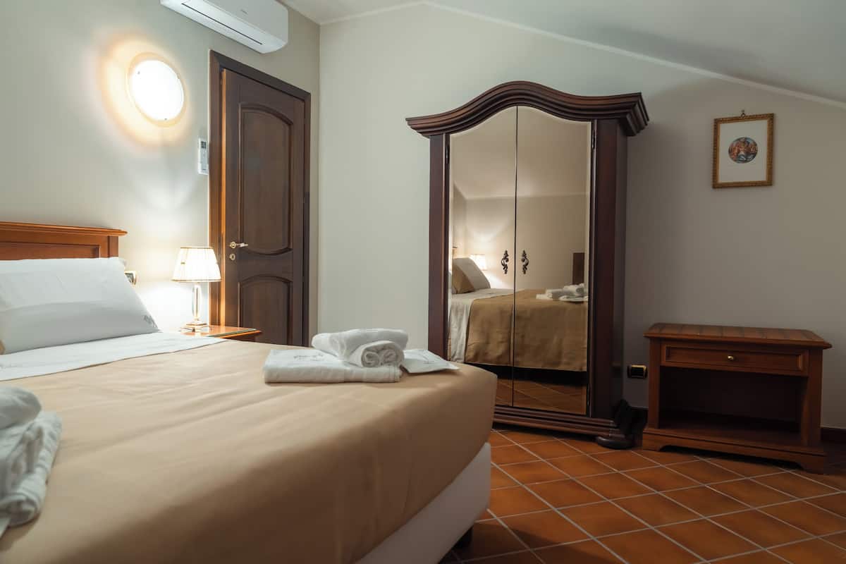 A hotel room with a bed, a wardrobe, a bedside table, and a lamp.