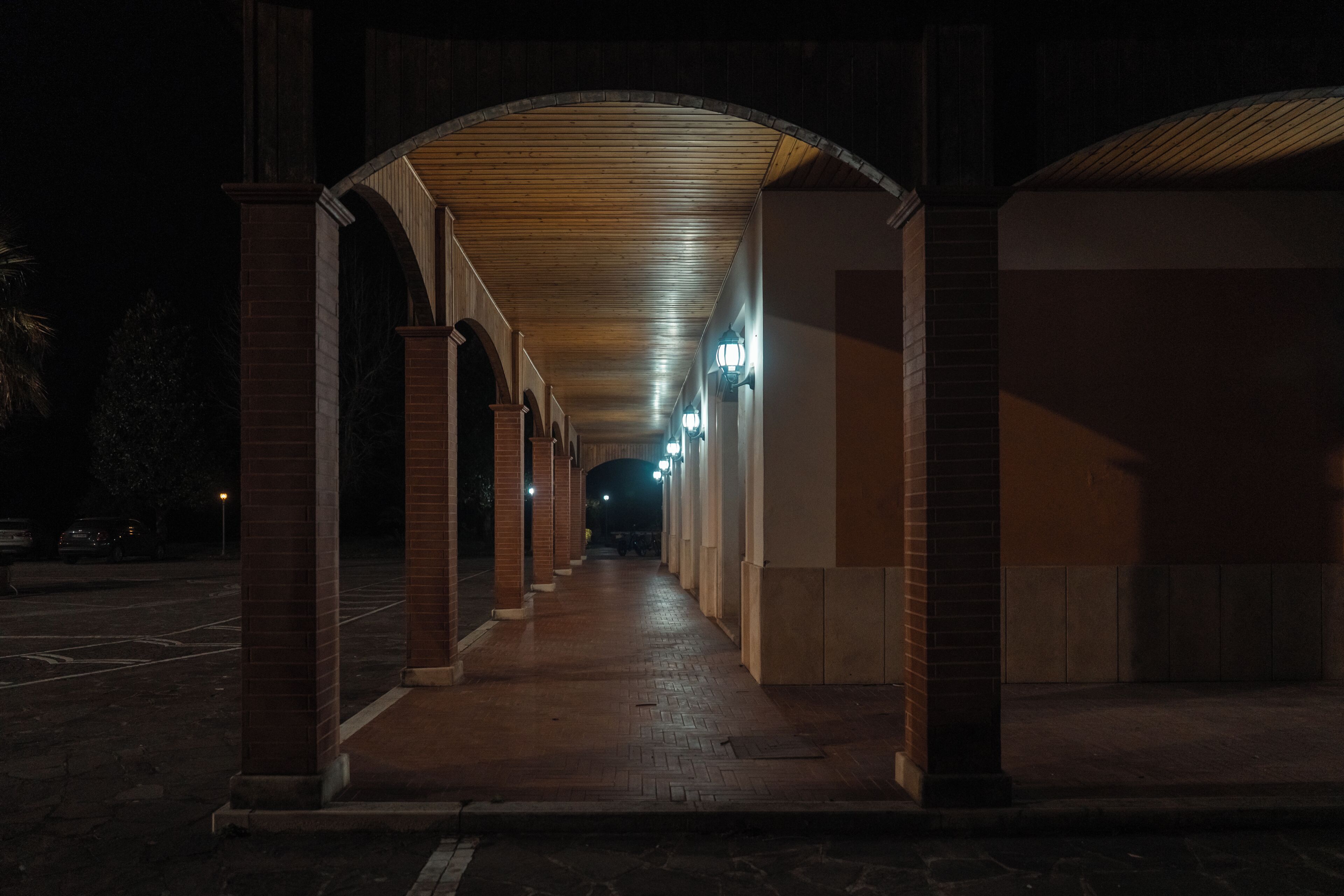 A covered walkway with brick columns and overhead lighting.