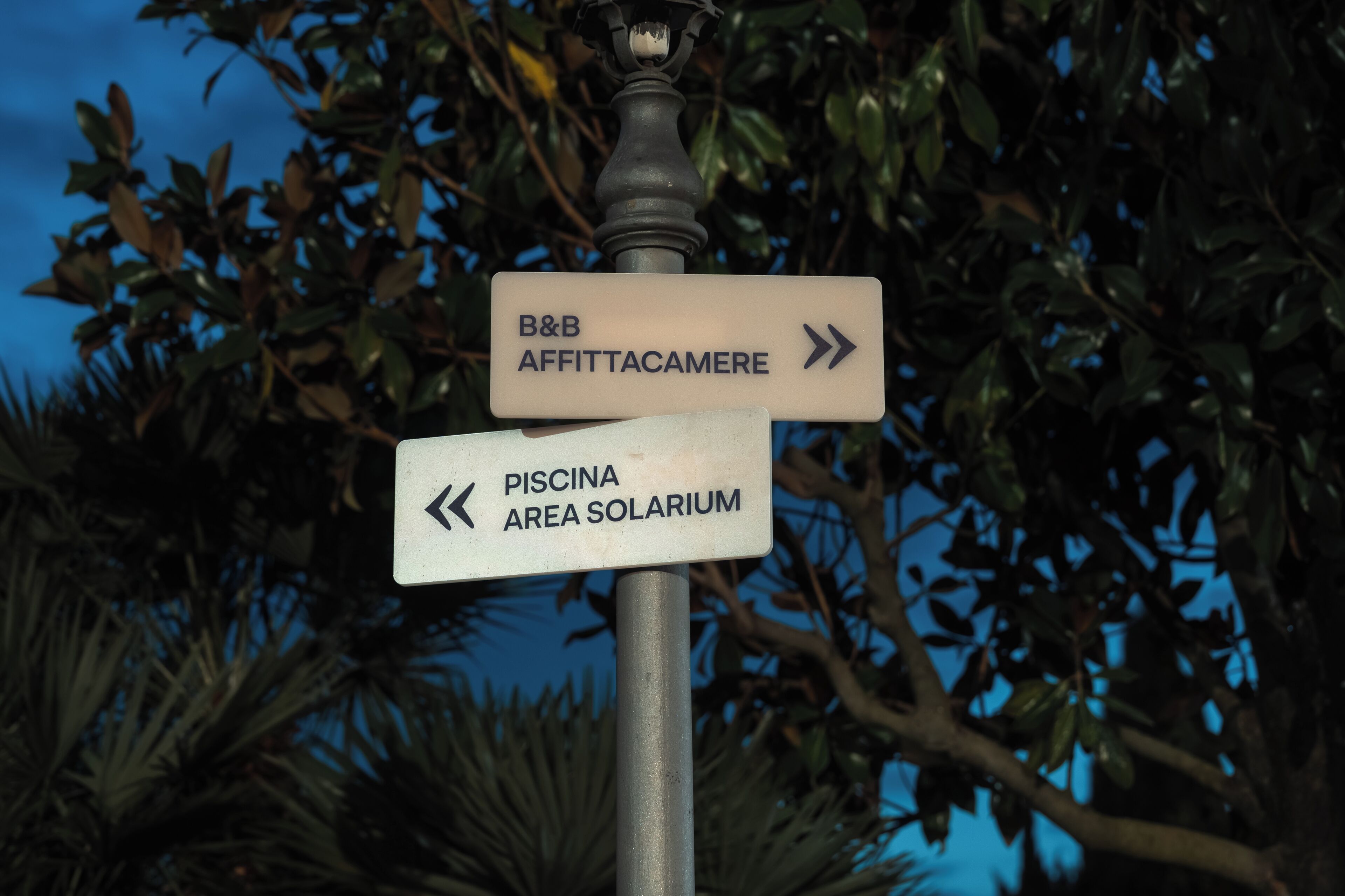 A directional signpost with arrows pointing to 'B&B AFFITTACAMERE' and 'PISCINA AREA SOLARIUM'.