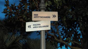 A directional signpost with arrows pointing to 'B&B AFFITTACAMERE' and 'PISCINA AREA SOLARIUM'.