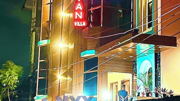 Een gebouw met een opvallend neonbord waarop 'MAXIMIAN VILLA' staat.