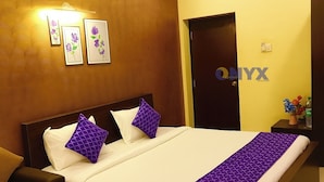 Een hotelkamer met een bed, nachtkastjes, een deur en kunstwerken aan de muur.