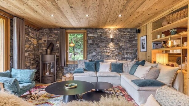 Ein gemütliches Wohnzimmer mit Steinwand, Kamin, Sofa und Couchtisch.