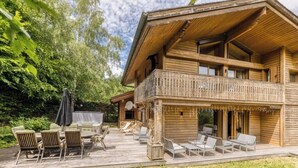 Eine Holzhütte mit Balkon, Sitzgelegenheit im Freien und einer Terrasse.