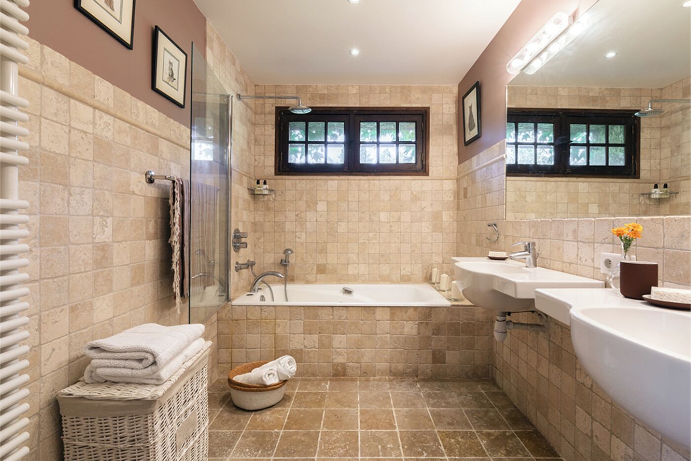 Een badkamer met een bad, twee wasbakken, een douche en een raam.