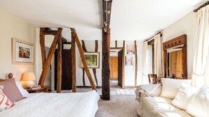 A bedroom with a bed, a sofa, wooden beams, a lamp, and a framed picture on the wall. - Tarrit de Bas with gated pool and total privacy (Castelnau d’Auzan Labarrère)
