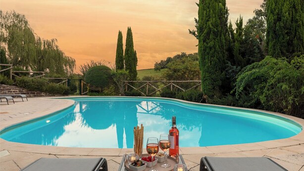 A swimming pool with lounge chairs and a table set for a meal, surrounded by trees and a sunset sky. - Tarrit de Bas with gated pool and total privacy (Castelnau d’Auzan Labarrère)
