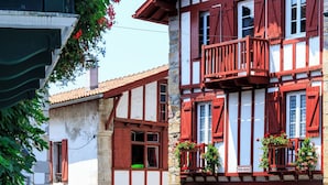 A traditional half-timbered building with balconies, a stone base, and flower boxes. - Villa Souraïde with pool, games room and Basque views (Souraide)