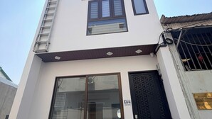 A modern building with a glass entrance, a metal ladder, and a black door with a geometric pattern. - Corgi House Da Nang- Airport City Center (Da Nang)
