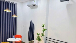 A hotel room with a bed, a table with chairs, an air conditioner, and a projector mounted on the wall. - Corgi House Da Nang- Airport City Center (Da Nang)