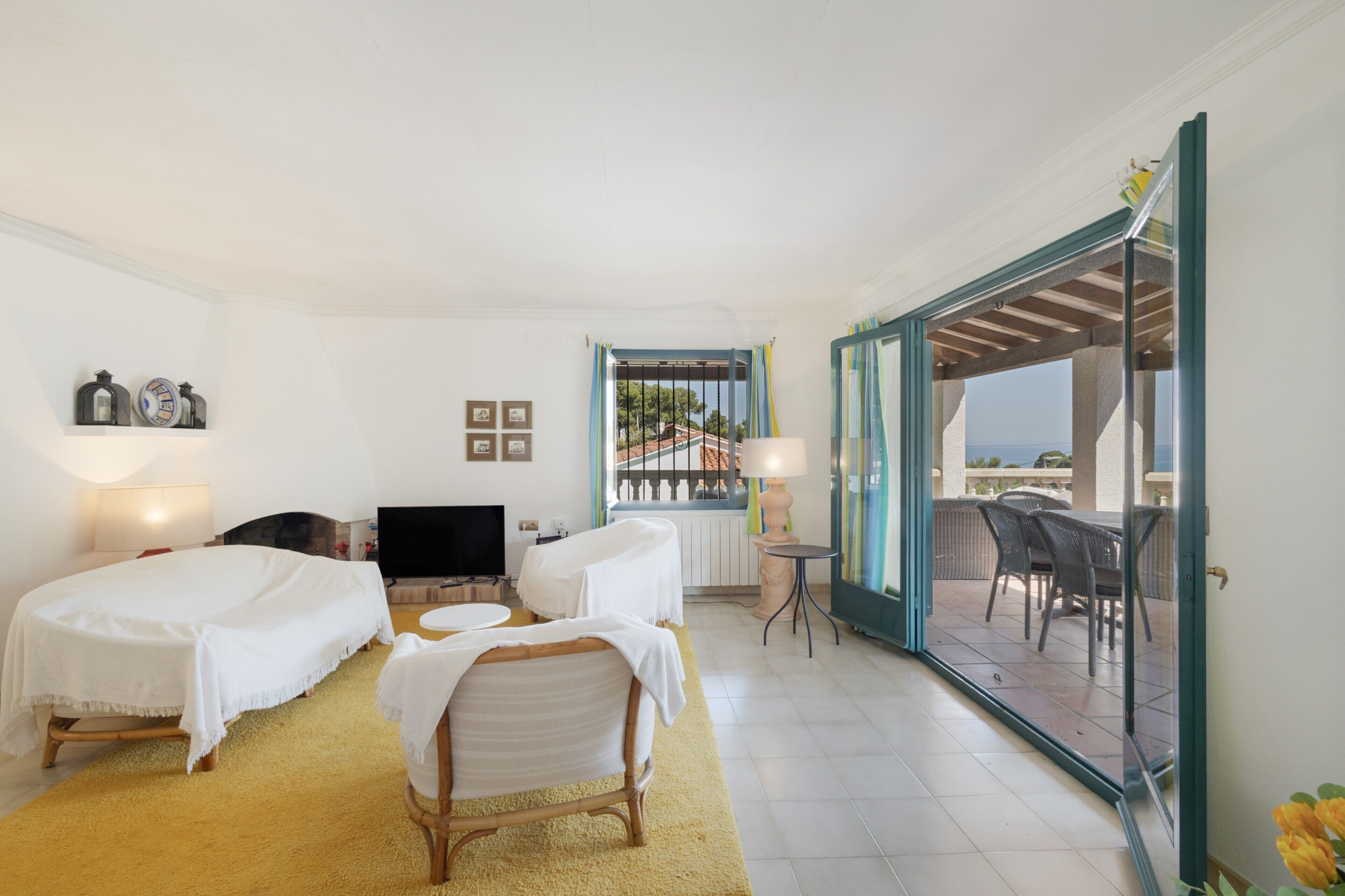 Ein Hotelzimmer mit zwei Betten, einem Fernseher, einem kleinen Tisch, einem Sessel und einem Balkon mit Aussicht.
