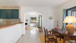 A kitchen with wooden cabinets, a dining area with a table and chairs, and a hallway leading to a bedroom. - Villa with Pool 700 Meters from the Beach (Begur)