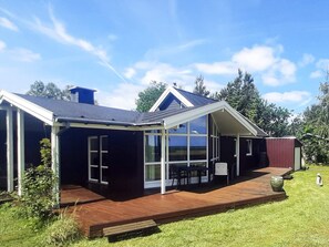 A modern house with a large glass window, a wooden deck, and a dark exterior. - 5 Star Holiday Home in Hadsund (Hadsund)