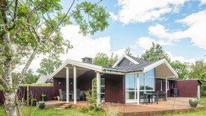 Een modern huis met een overdekte patio, een terras en een groot raam.