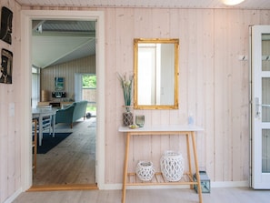 Ein Zimmer mit Holzwänden, einem weißen Konsolentisch mit dekorativen Vasen, einem Spiegel und einer Tür zu einem weiteren Raum.
