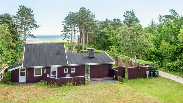 Een huis met een schuin dak, een veranda en uitzicht op het strand.