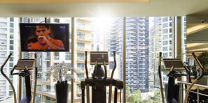 A gym with exercise equipment, a television, and a view of high-rise buildings. - LUX The JW Marina Studio 4 (Dubai)