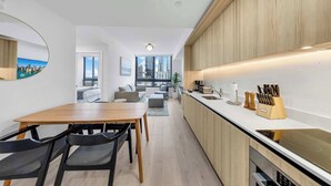 Een moderne keuken met een ingebouwde kookplaat, houten kasten en een eethoek met een tafel en stoelen.