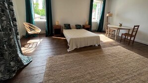 A bedroom with a bed, a chair, a table, and a lamp. - Large family home (Savignac-les-Églises)