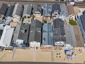 Eine Luftaufnahme eines Küstenhotels mit mehreren Gebäuden, einem Strand und einem Parkplatz.