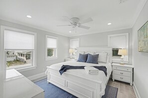 A bedroom with a bed, nightstands, a ceiling fan, and large windows. - Stunning Manasquan getaway featuring a private pool and hot tub where comfort meets coastal luxury. (Manasquan)