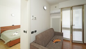 Moderni huone, jossa on sänky, sohva, patteri ja liukuovellinen lasiterassi.
