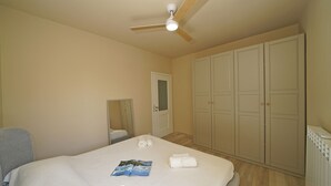 Habitación de hotel con cama, ventilador de techo, armario y puerta.