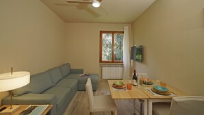 Una habitación con ventilador de techo, una mesa de comedor con platos y vasos, un sofá y una lámpara.