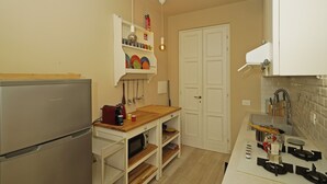 Una cocina compacta con un refrigerador, una encimera de madera, un lavabo y una estufa.